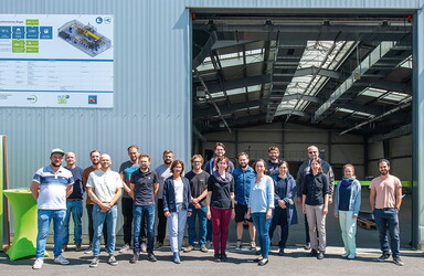 Gruppenbild von mehreren Personen vor einer Halle.