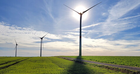 Windkrafträder die auf einen grünen Feld stehen.