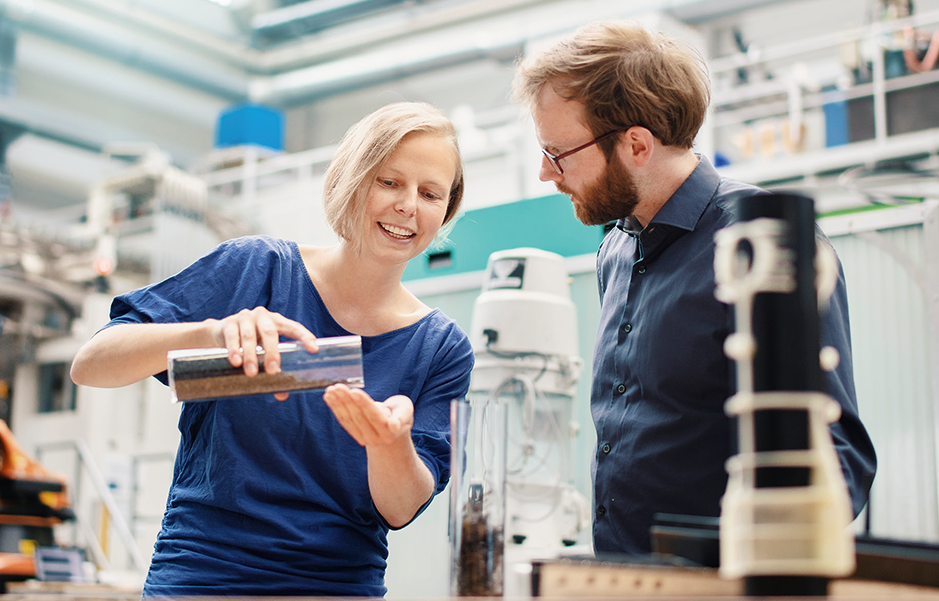 Eine Frau zeigt einem Mann Dinge in einem Labor.