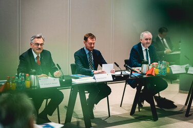 Michael Kretschmer und zwei weitere Männer bei einer Konferenz.