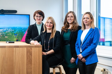 Vier Frauen schauen lächelnd in die Kamera.