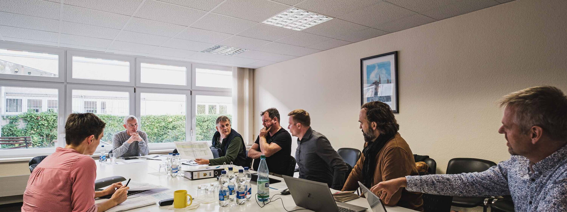 Ein Konferenzraum in dem sechs Männer und eine Frau sitzen und ein Gespräch führen.