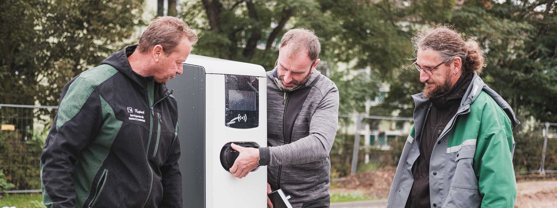 Drei Männer stehen vor einen Parkautomaten.