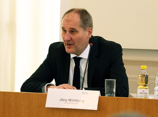 Herr Jörg Mühlberg steht am Pult und hält eine Rede