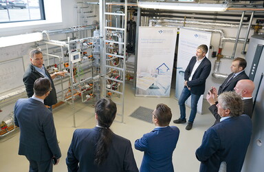Männern in Anzügen wird in einer Hochschule etwas über Elektrizität erklärt.