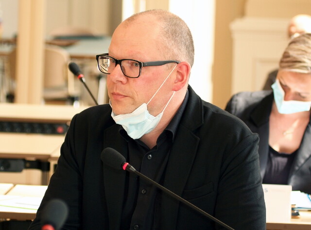 ein Mann sitzt an einem Tisch mit Mikrofon