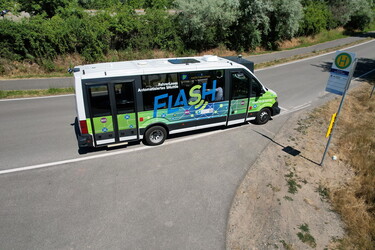Ein kleiner Bus an einer Bushaltestelle.