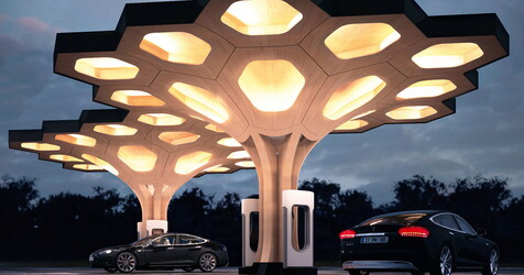 zwei autos die unter einer futuristischen Tankstelle stehen.