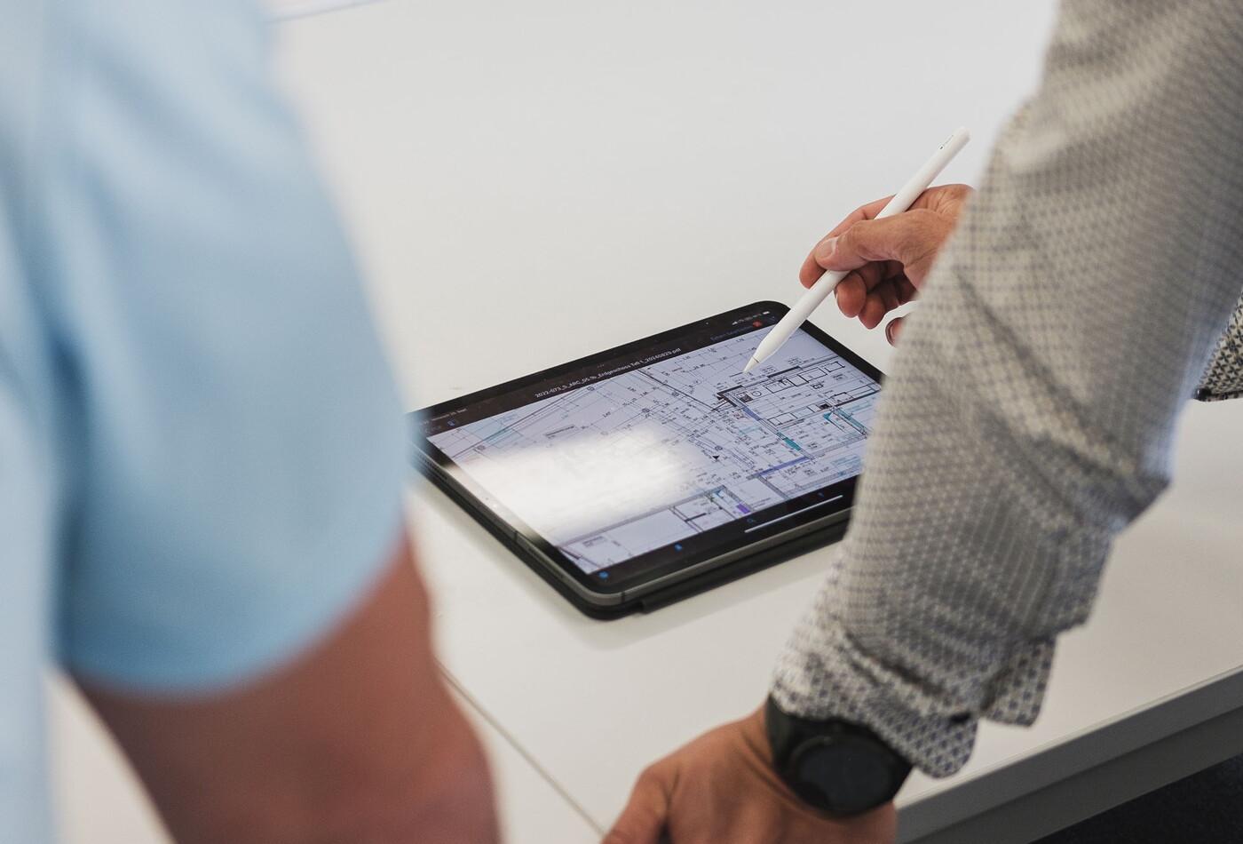 eine Aufnahme von einem Tablet auf dem zwei Personen drauf schauen und sich durch klicken.