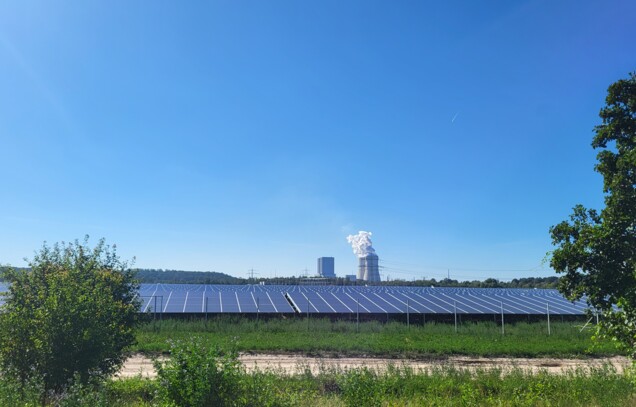 Eine Solaranlage mit einem Kraftwerk im Hintergrund.
