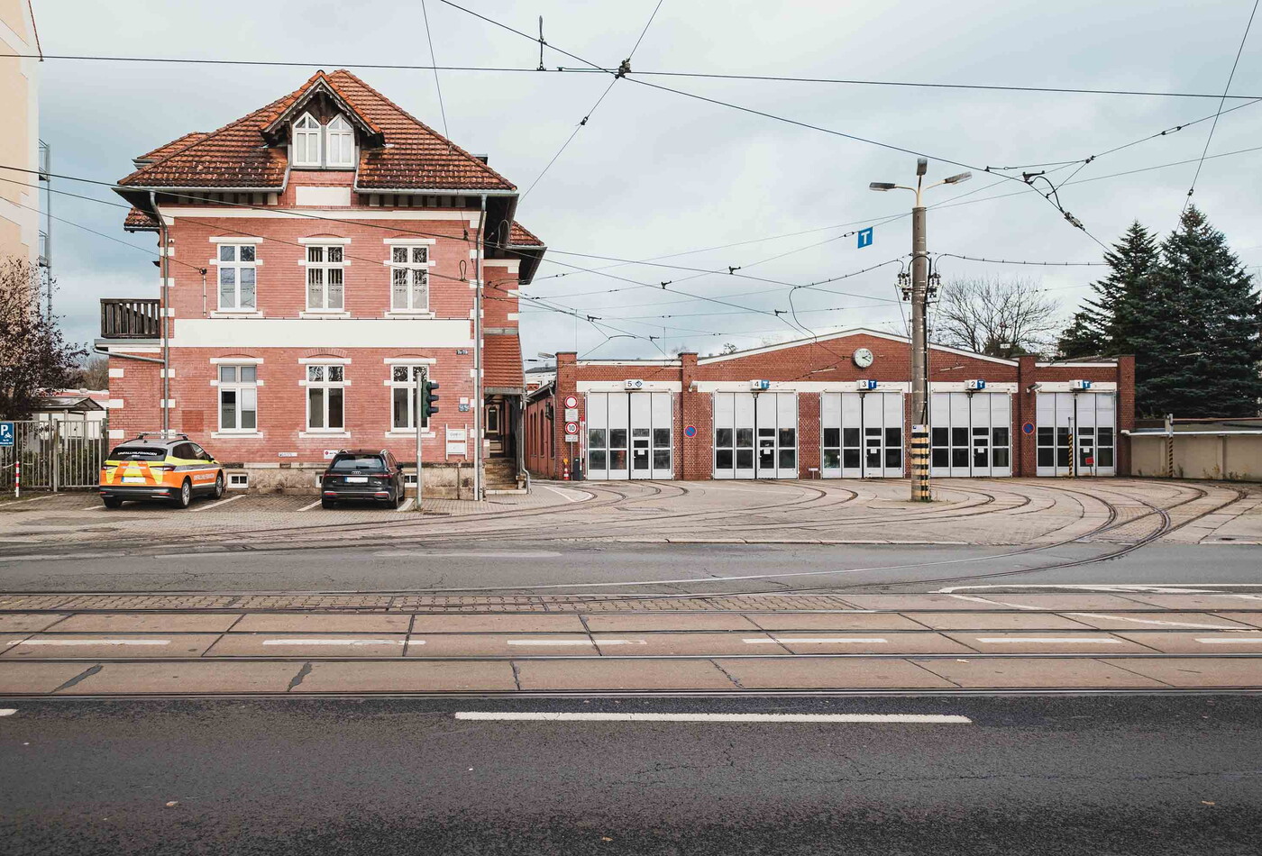 Ein braunes Gebäude wo die Straßenbahn Schienen hinein führen.