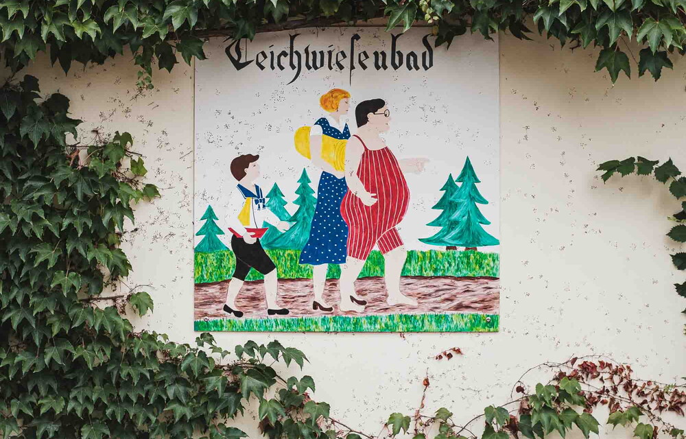 Ein altes Plakat mit der Aufschrift Teichwiesenbad, welches an ein Haus angebracht ist