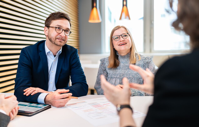 Mehrere Personen sitzen diskutierend an einem Tisch.