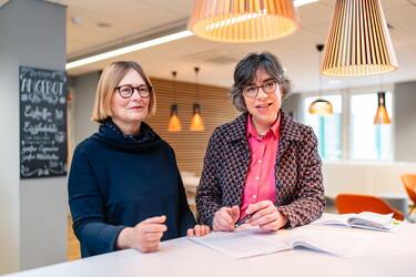 Zwei Frauen besprechen ein Dokument an einem Tisch.