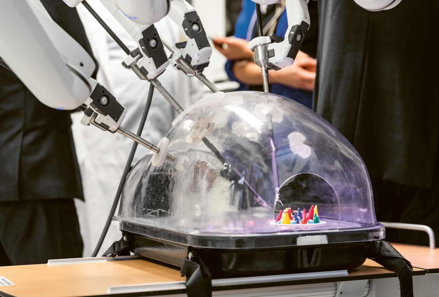 Personen stehen um einen  Roboter, dessen Greifarme arbeiten
