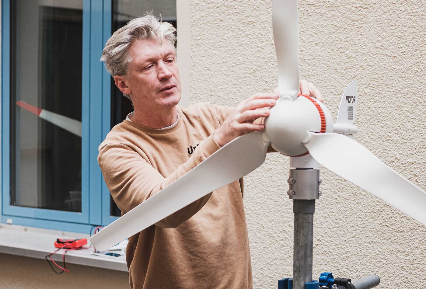 Ein Mann der ein Modell eines Windkraftwerkes in den Händen hält