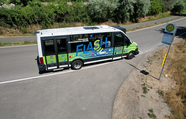 Ein kleiner Bus an einer Bushaltestelle.
