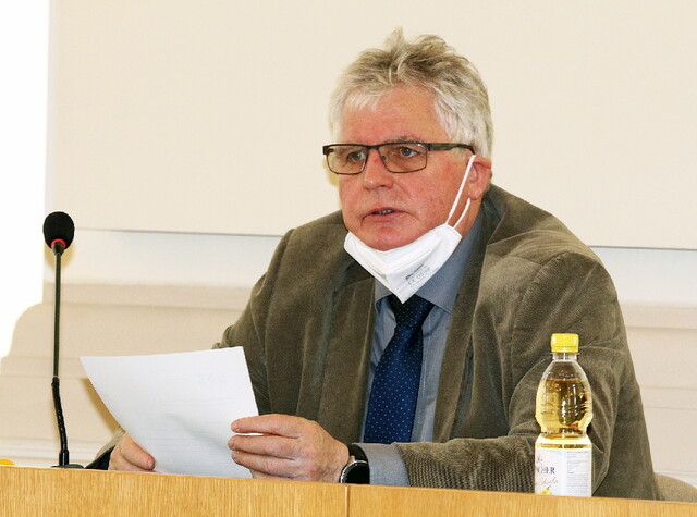 ein Mann sitzt am Pult und hält eine Rede