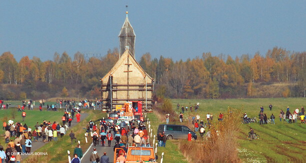 viele Menschen befinden sich auf dem Weg und auf der Wiese und in der Mitte des Hintergrunds befindet sich eine Kirche