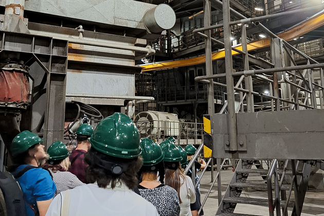 Schüler mit dunkelgrünen Kopfschutz laufen in eine Fabrik.