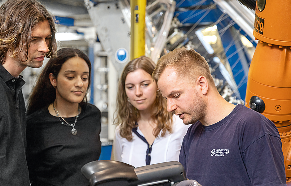 Ein Mann demonstriert Studenten die Funktionsweise einer Maschine.