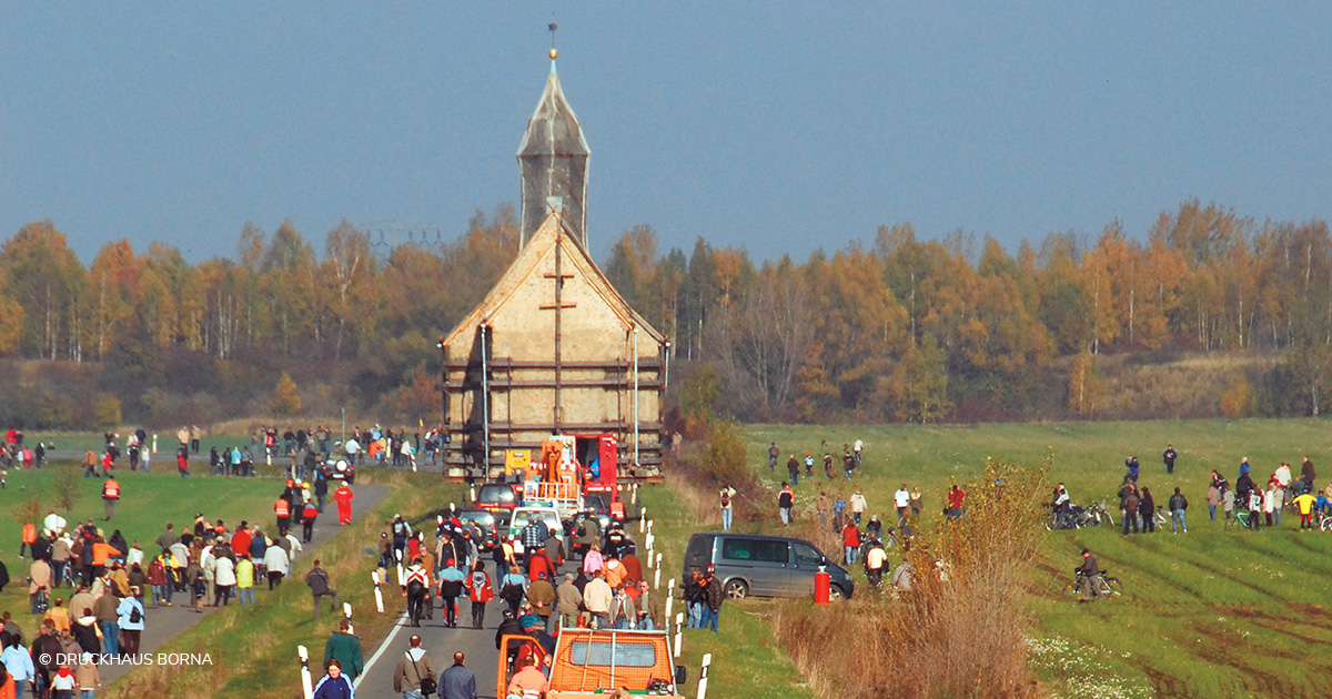 viele Menschen befinden sich auf dem Weg und auf der Wiese und in der Mitte des Hintergrunds befindet sich eine Kirche